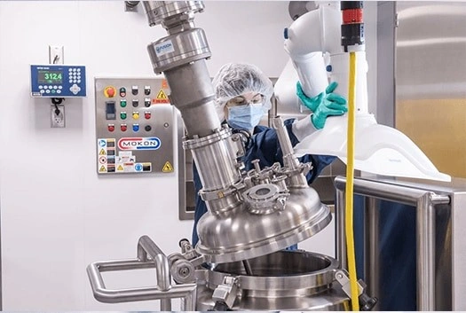 Bio-Techne technician operating a stainless steel bioreactor in a GMP manufacturing suite for animal-free recombinant cytokine production